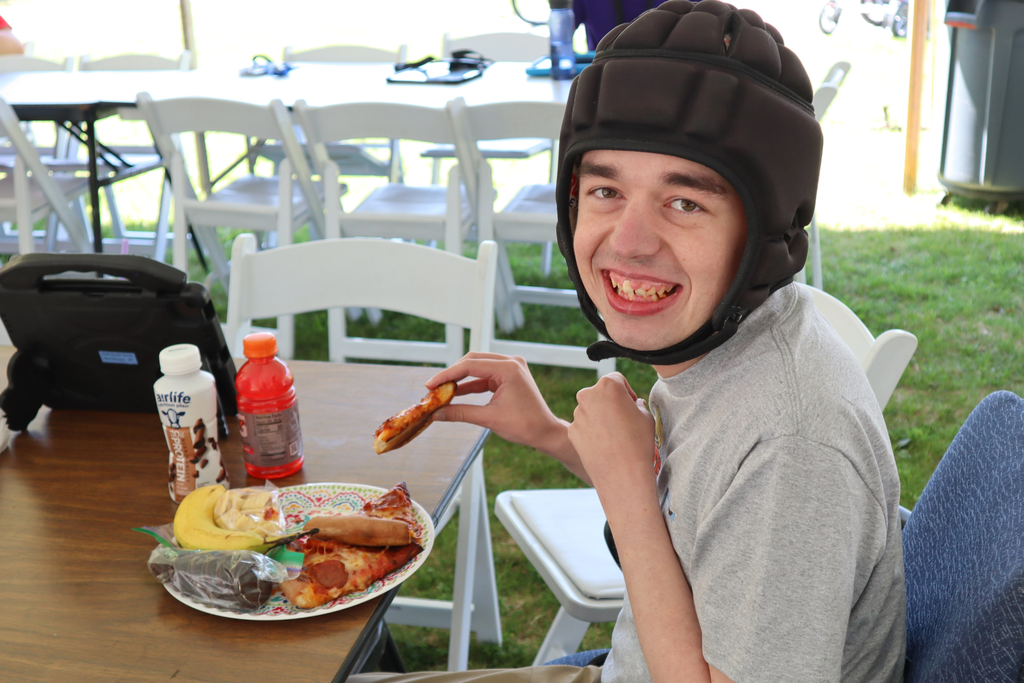 Transition Campus student smiling while eating pizza at the annual picnic.