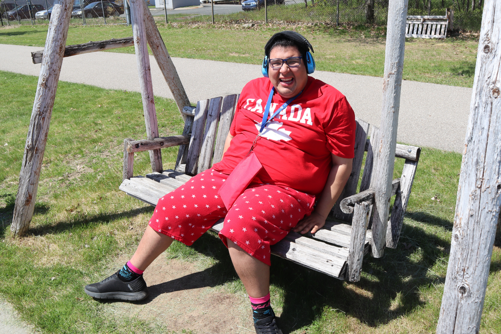 Transition campus student smiling while sitting on a wooden porch swing at the annual Transition Campus picnic.