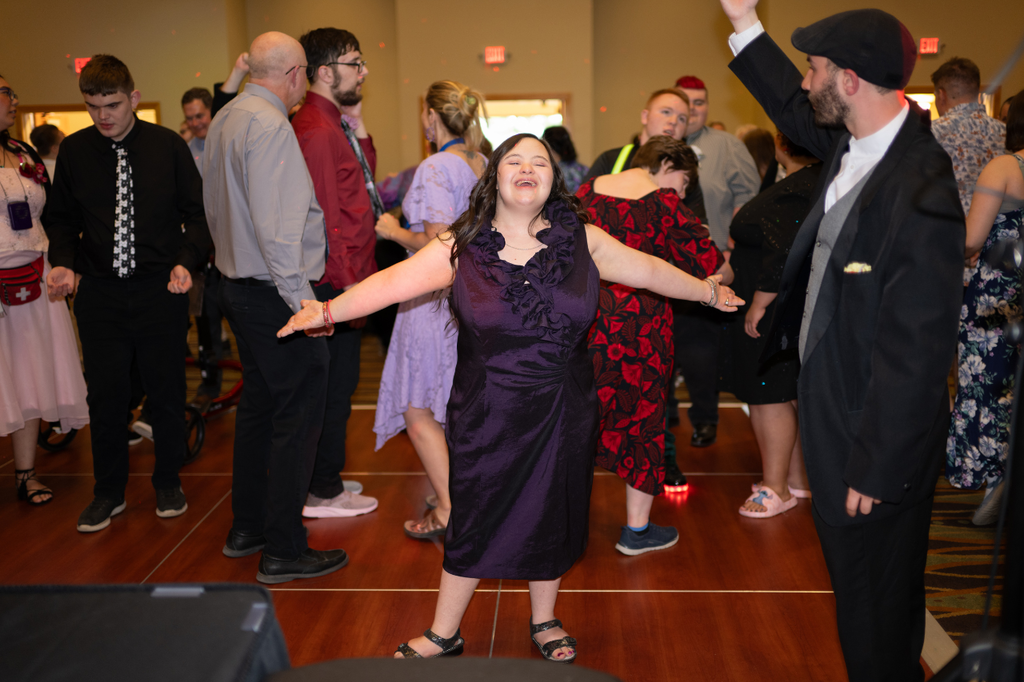Transition Campus student standing triumphantly in the middle of the dance floor, smiling, with arms stretched out.