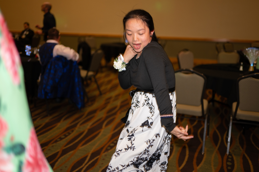 Transition Campus student wearing a white and black floral skirt and a black top dancing on the prom dance floor.