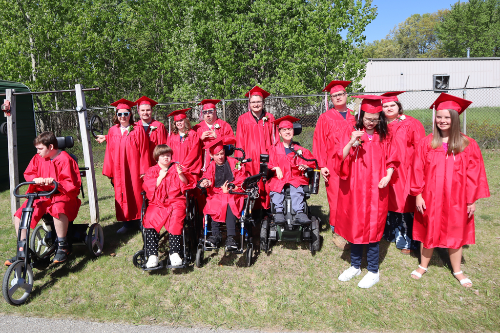 2026 Transition Campus graduates posing for a group photo wearing their red cap and gowns.