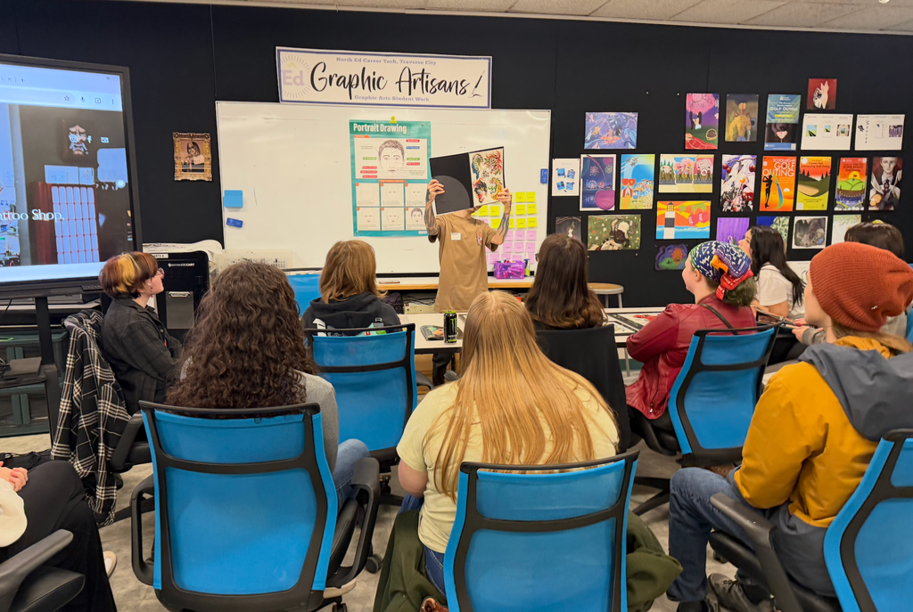 Tony Diaz holding presenting their portfolio in front of the North Ed Career Tech Graphic Arts class.
