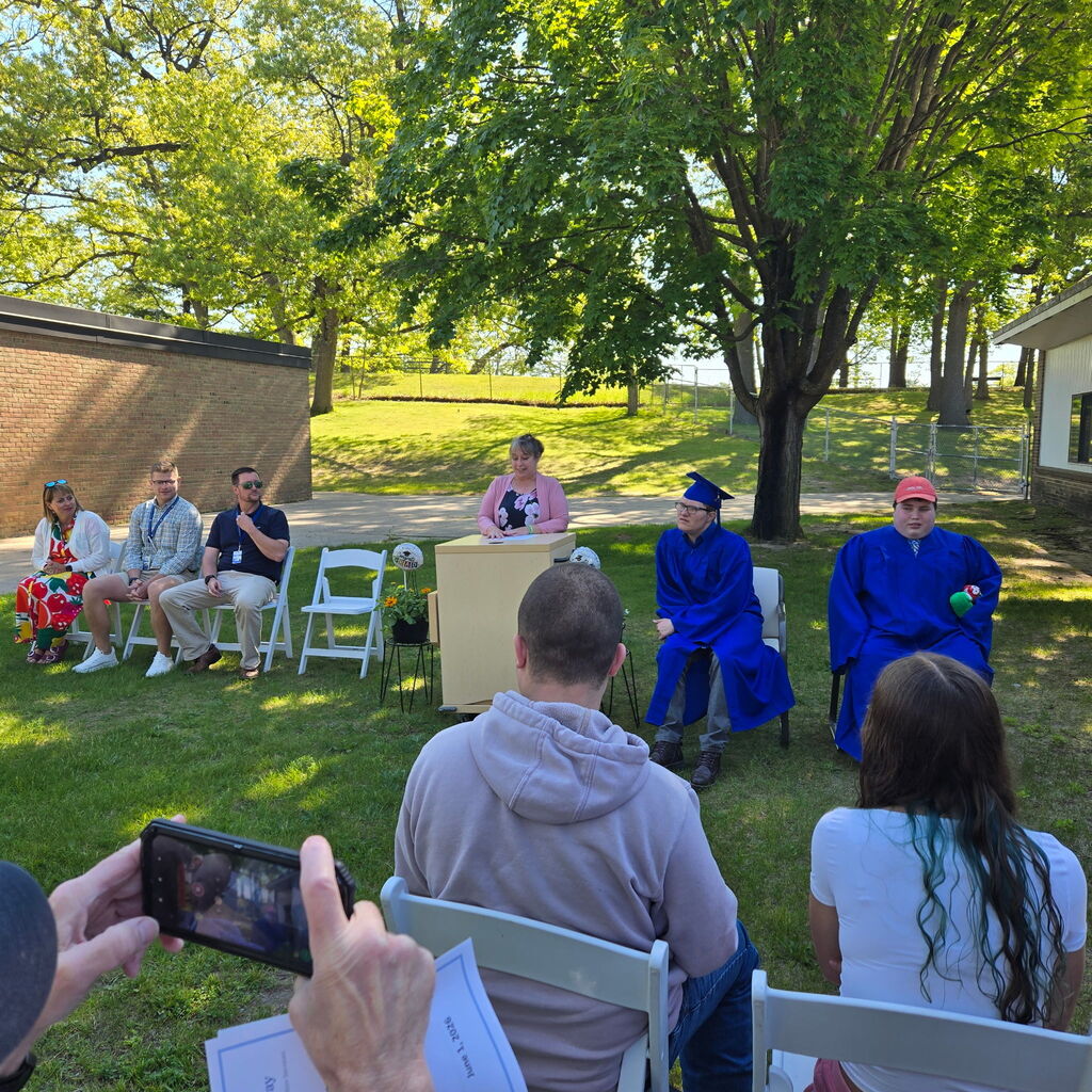 2026 Bridgeway Program graduates, staff and supporters sitting outside during the ceremony. 