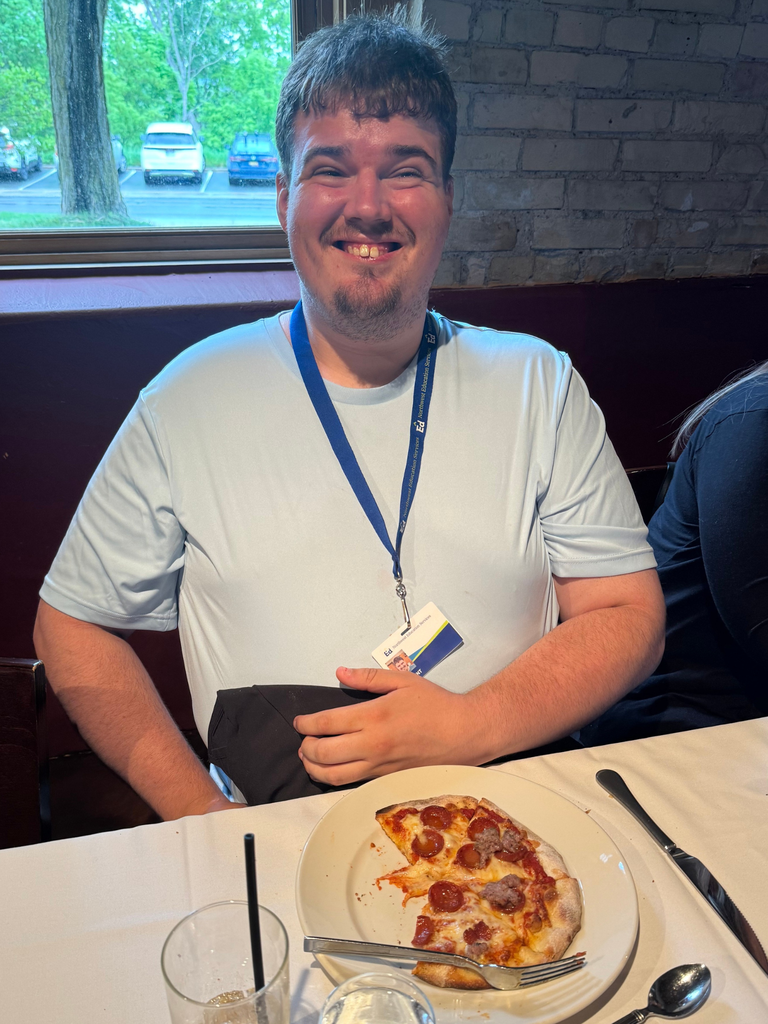 Transition Campus Work Experience Program student, smiling for a photo at lunch with their pizza.