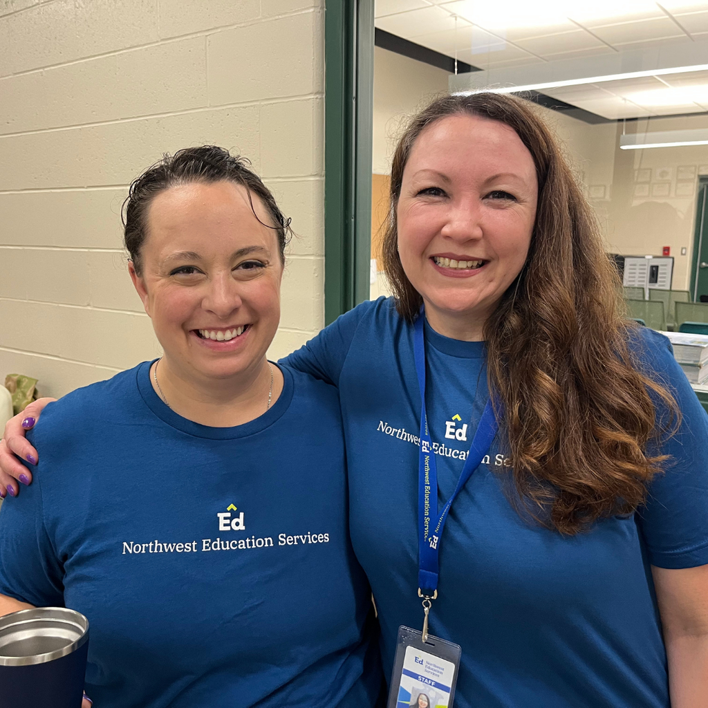 Two North Ed staff members wearing blue Northwest Education Services t-shirts, smiling and posing for a photo on Opening Day.