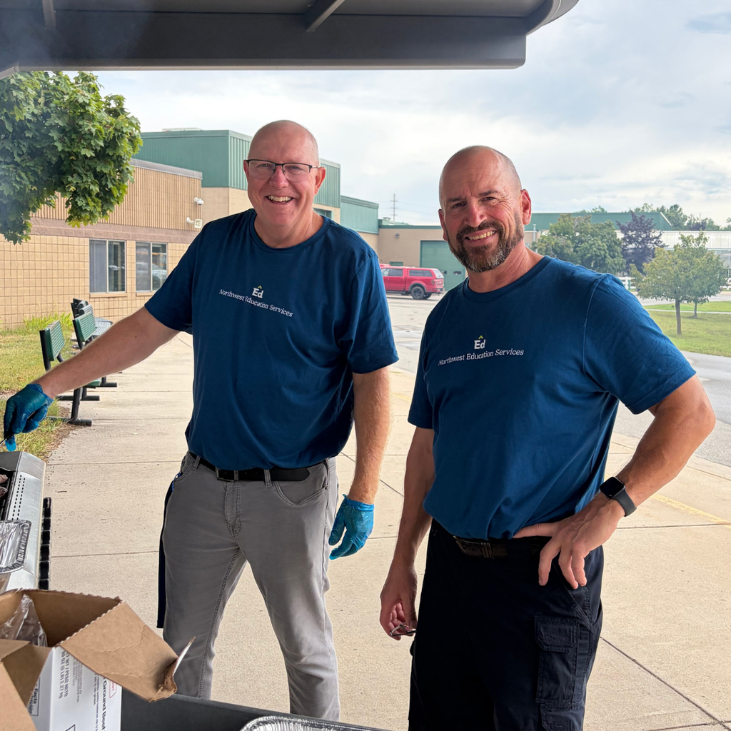North Ed staff members grilling outside of the Transition Campus building, wearing blue Northwest Education Services shirts.