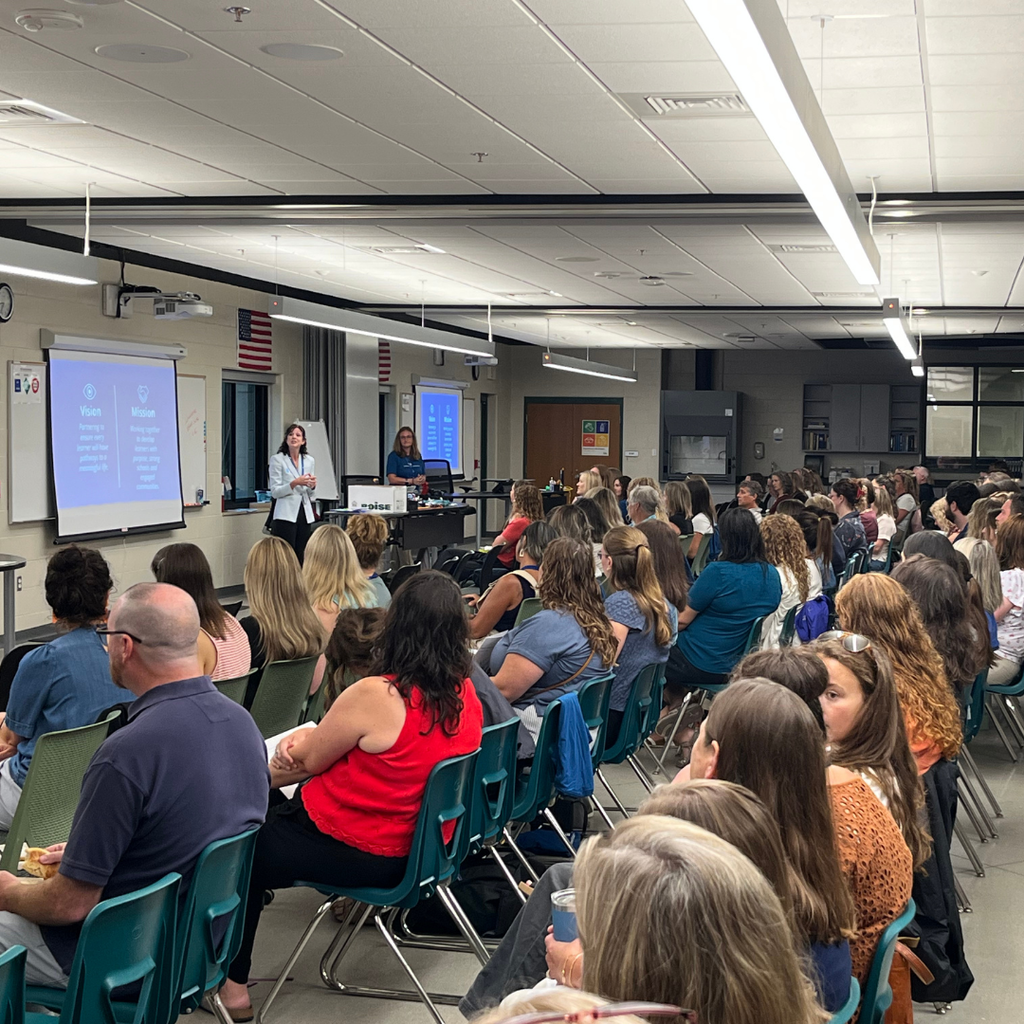 North Ed staff members sitting in a classroom watching Superintendent Tara Mager present for Opening Day. 