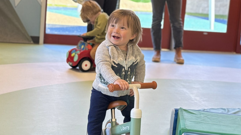 A child uses a toy bike inside a playroom at the Joseph C. Fisher Early Childhood & Family Center at Northwest Education Services.