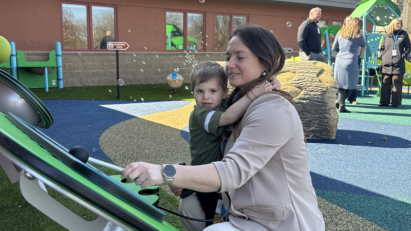 A woman holds a young boy as they explore the playground at the Joseph C. Fisher Early Childhood & Family Center at Northwest Education Services.