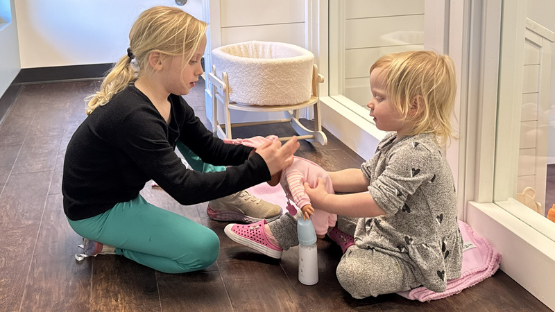 Two children play with a doll in a playroom at the Joseph C. Fisher Early Childhood & Family Center at Northwest Education Services.