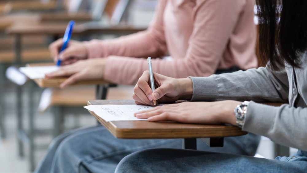 Students taking exams at school desk