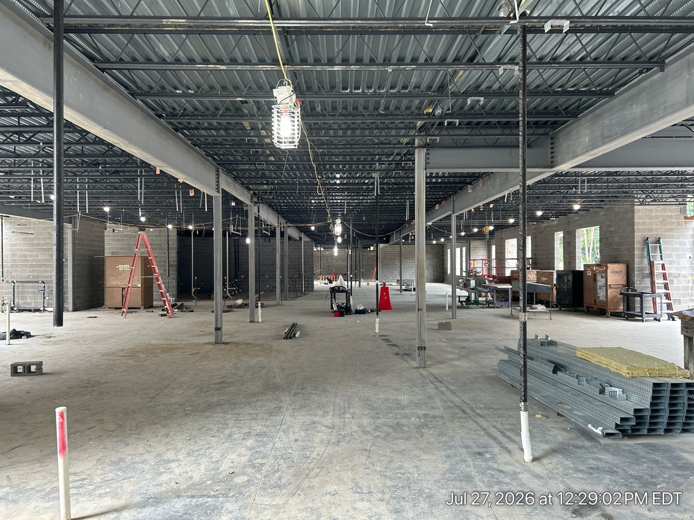 Steel framing continues to rise across the upper level while masonry crews build out the western section below. On the lower level, mechanical, electrical, and plumbing systems are being installed overhead as interior walls begin to define future learning spaces.