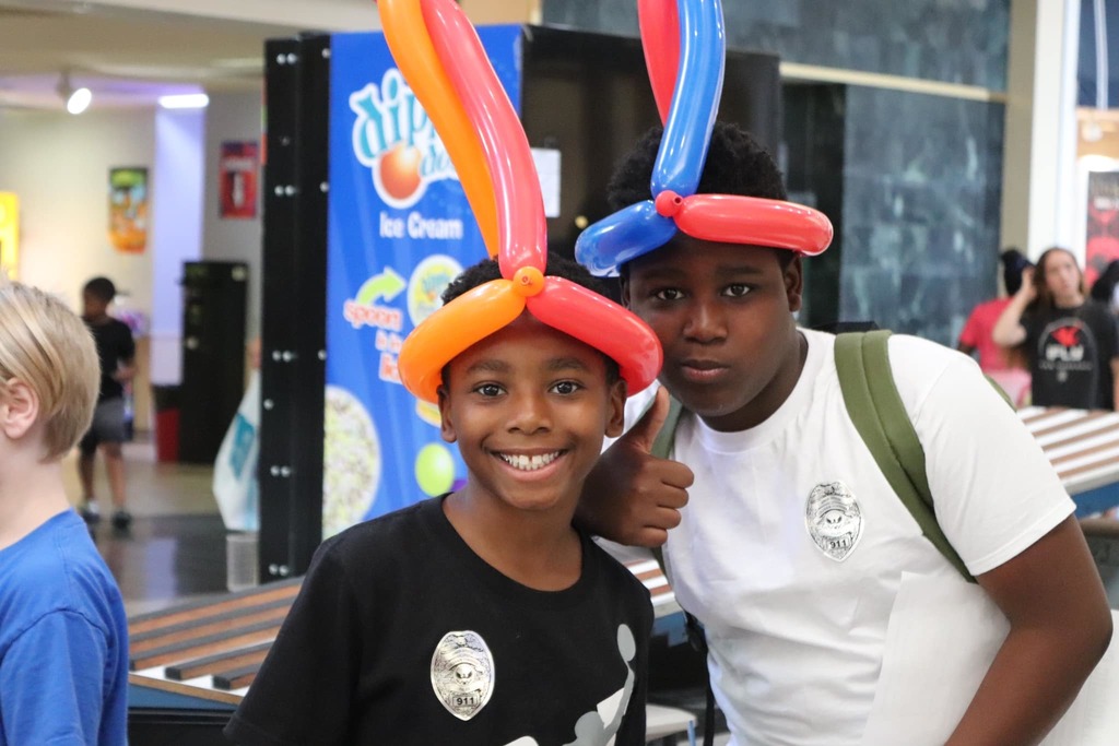 Two young boys in balloon hats smiling at the camera at the Health and Safety fair