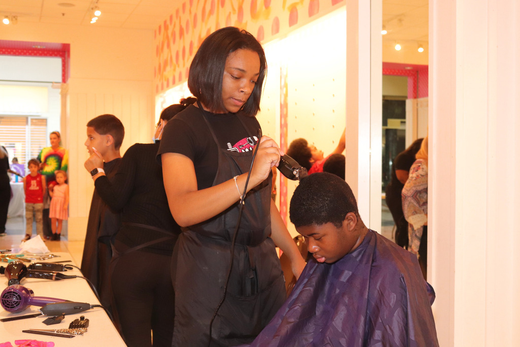 Woman giving young man a free haircut at Health and Safety Fair.