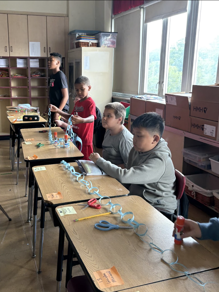 students laying paper chain across desks