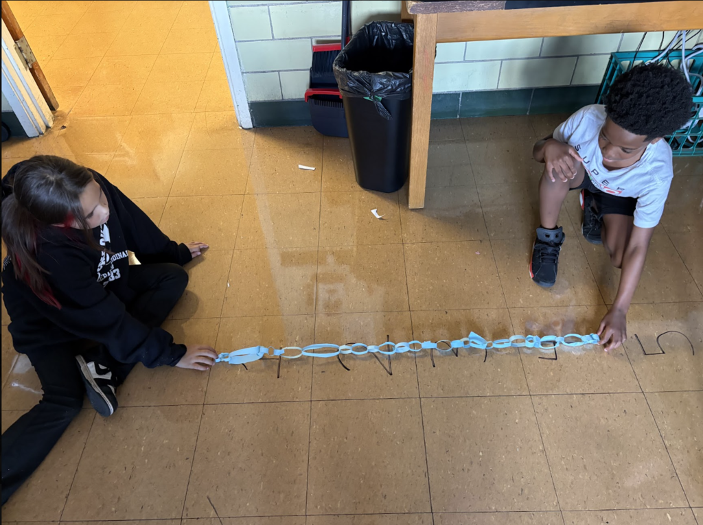 students measuring their paper chains on the floor