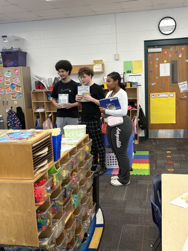Three students hold books