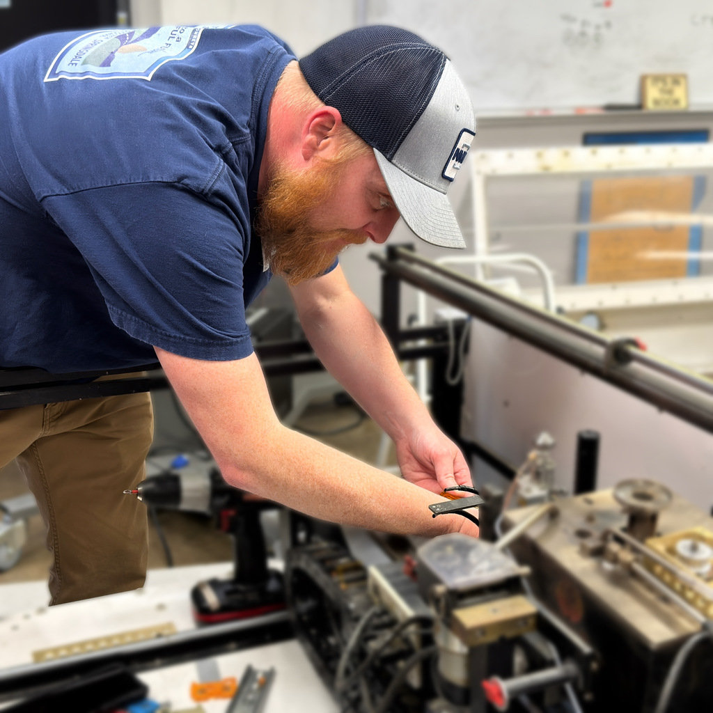 electronics and automation student and instructor work on a soldering machine