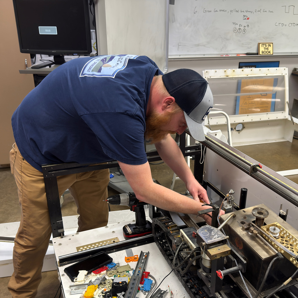 electronics and automation student and instructor work on a soldering machine