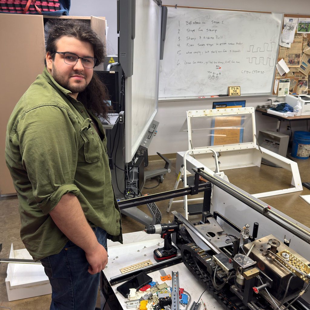 electronics and automation student and instructor work on a soldering machine