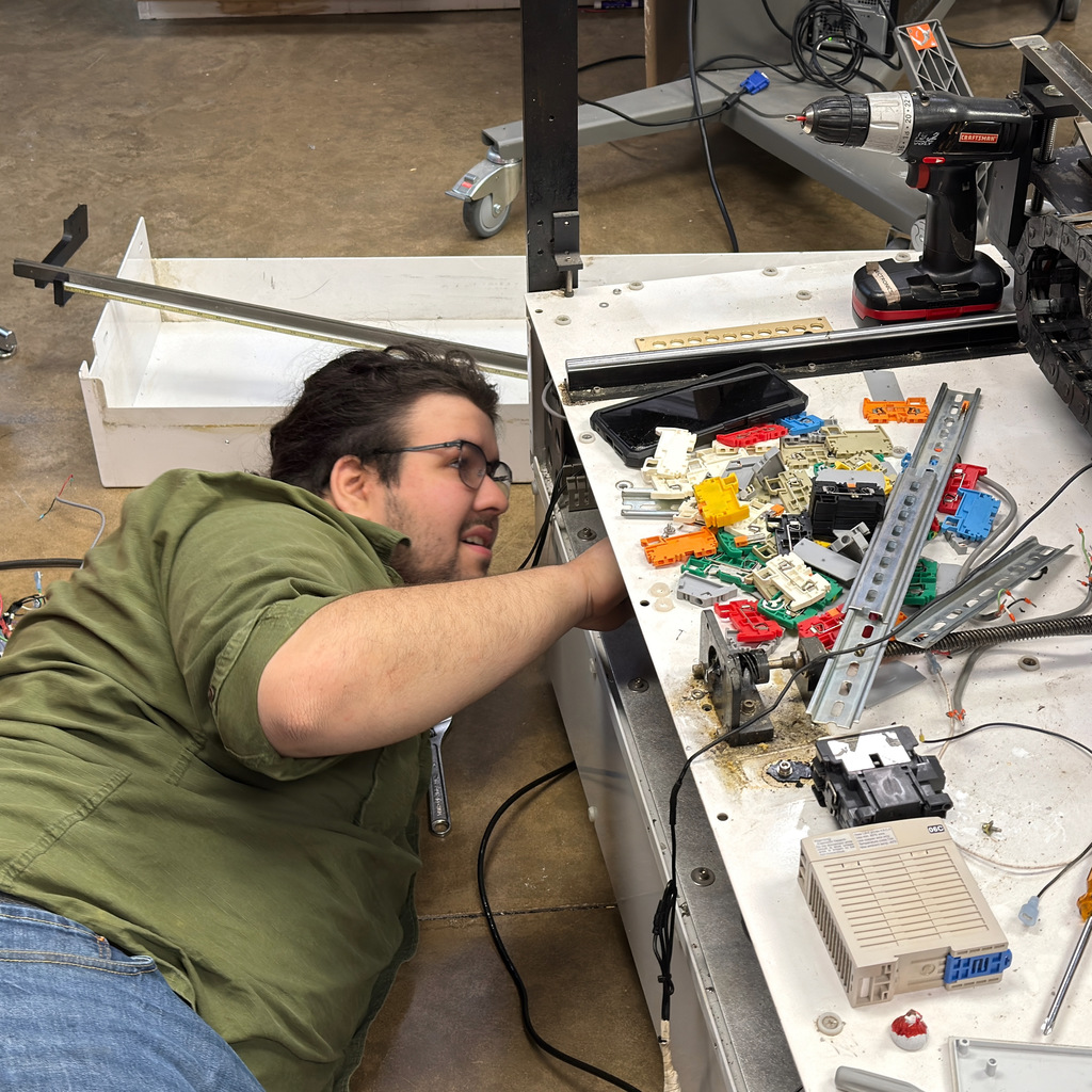 electronics and automation student and instructor work on a soldering machine