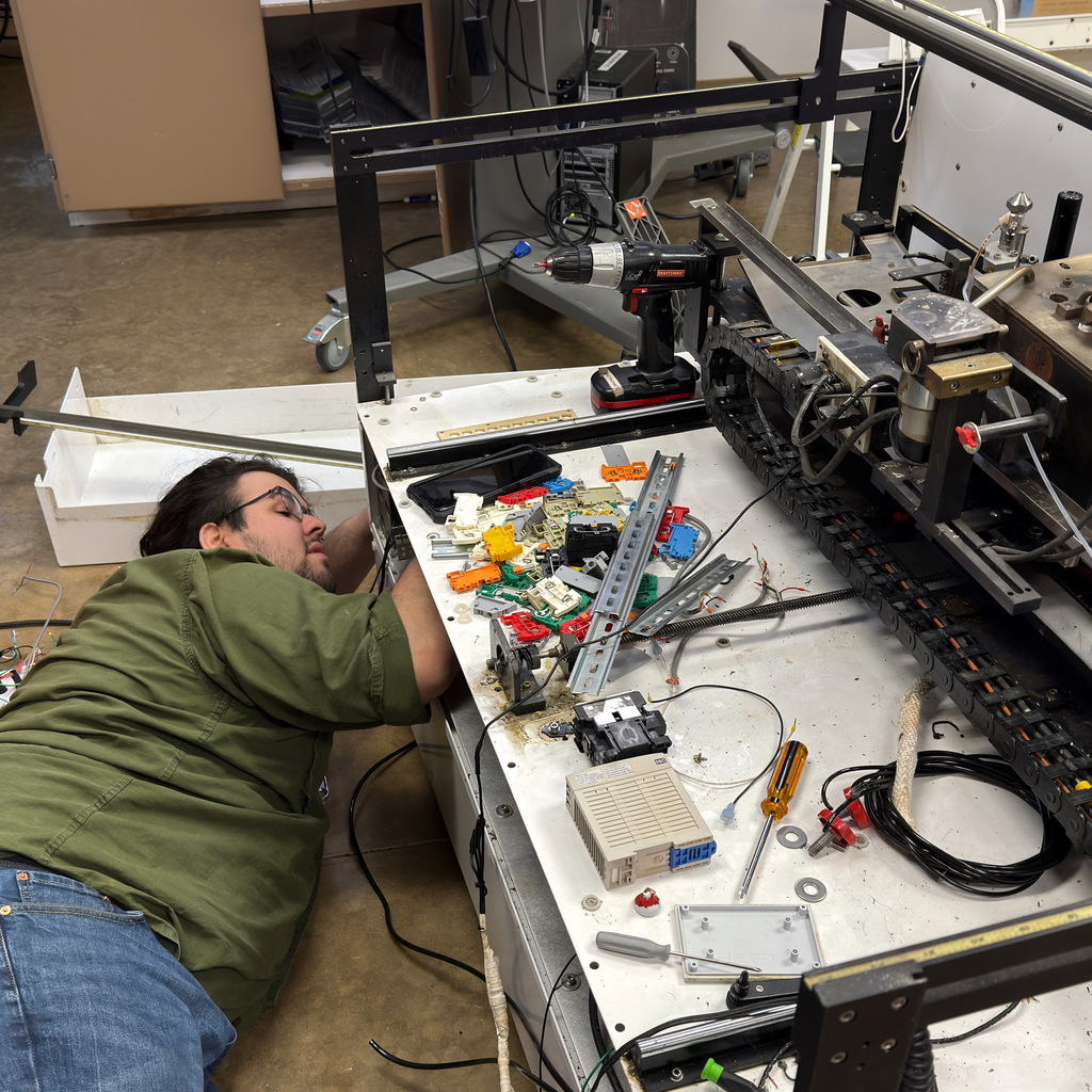 electronics and automation student and instructor work on a soldering machine
