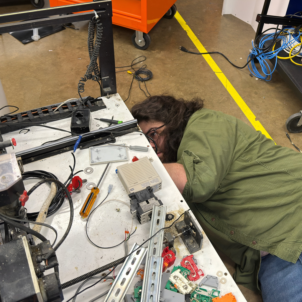electronics and automation student and instructor work on a soldering machine