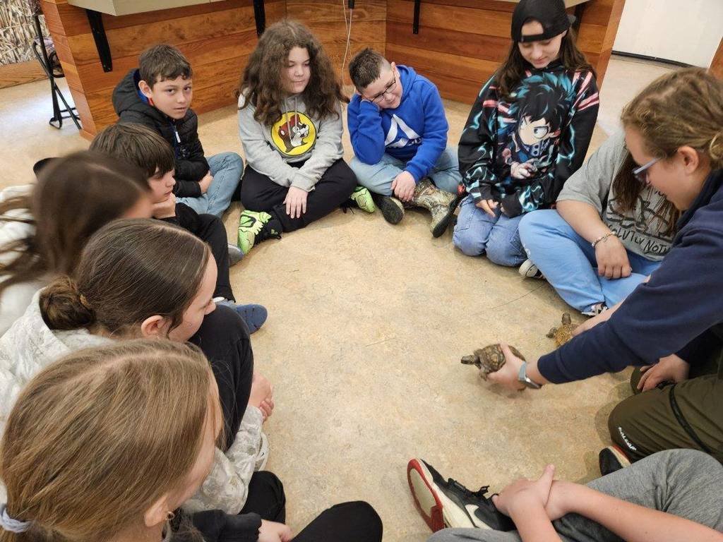kids watching a lady with a turtle