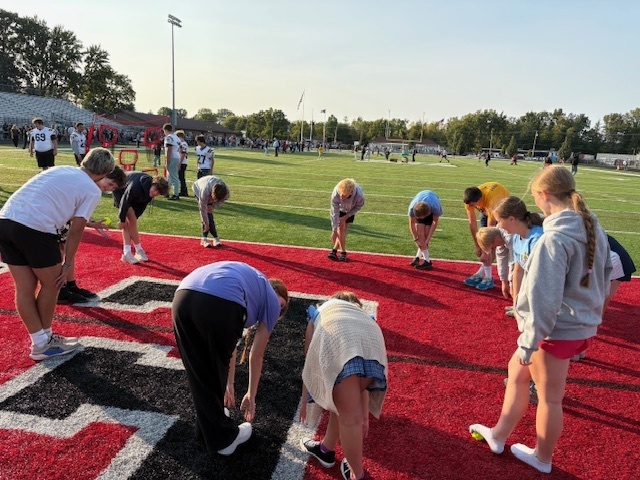 High School Cross Country and Track team doing stretches with the kids during Reading Under the Lights