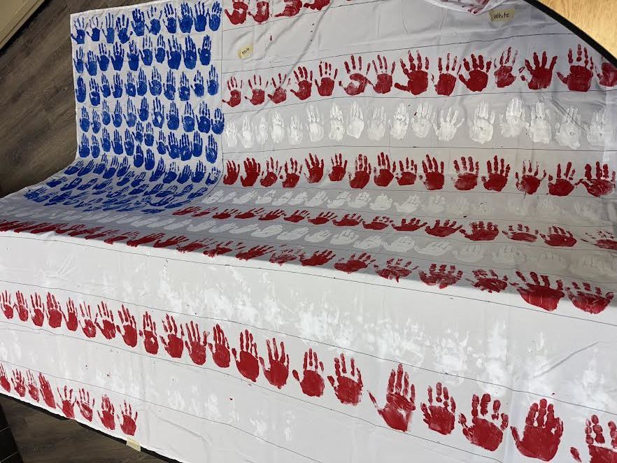 2nd & 3rd Graders at Pleasant Elementary collaborated to make a handprint flag in honor of our Veteran family members and friends. It is hanging on display in the gym/cafeteria.
