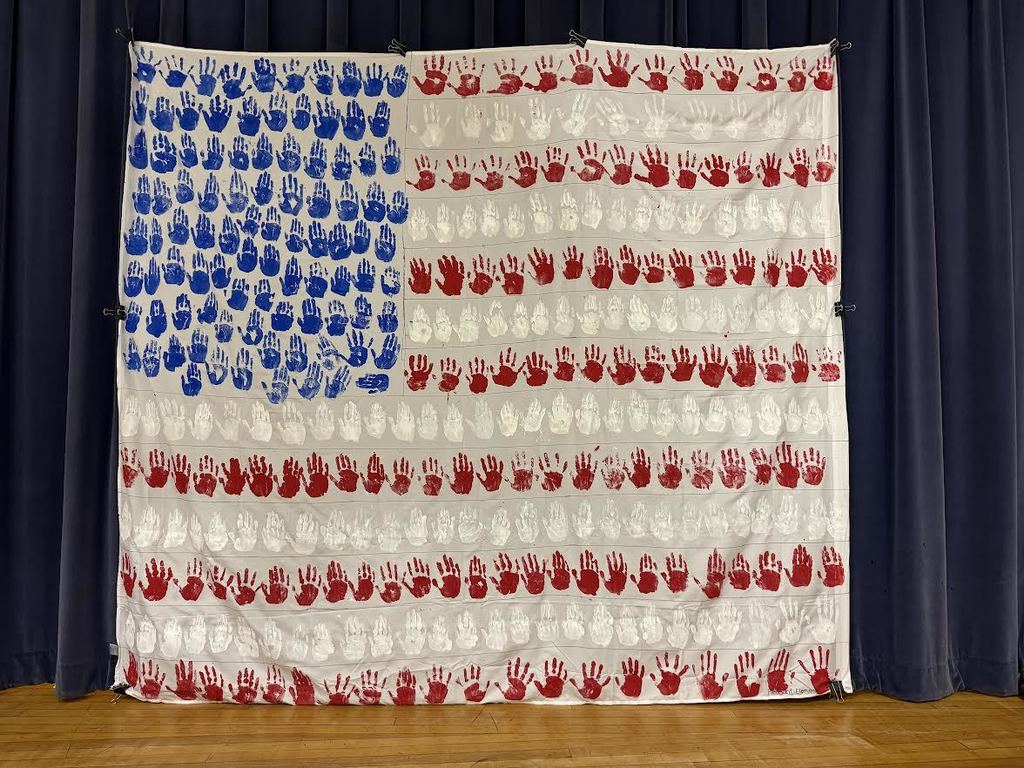 2nd & 3rd Graders at Pleasant Elementary collaborated to make a handprint flag in honor of our Veteran family members and friends. It is hanging on display in the gym/cafeteria.