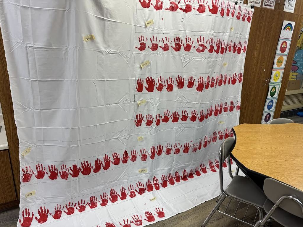2nd & 3rd Graders at Pleasant Elementary collaborated to make a handprint flag in honor of our Veteran family members and friends. It is hanging on display in the gym/cafeteria.