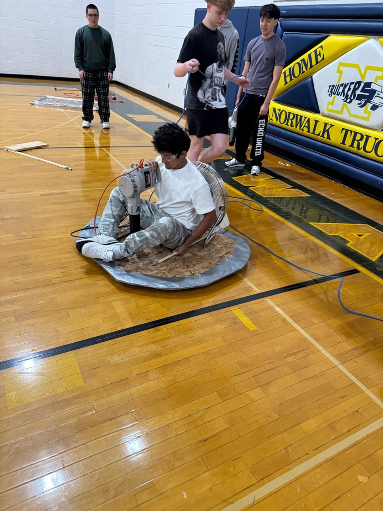 Victor Negrete test rides his hovercraft he built in Industrial Education 2 while his partner LJ Odell assists him with the power cord. 