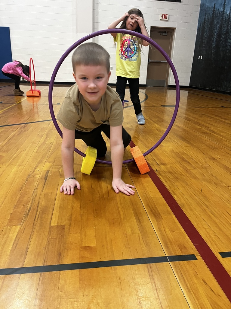 student crawling through a hula hoop on the gym floor