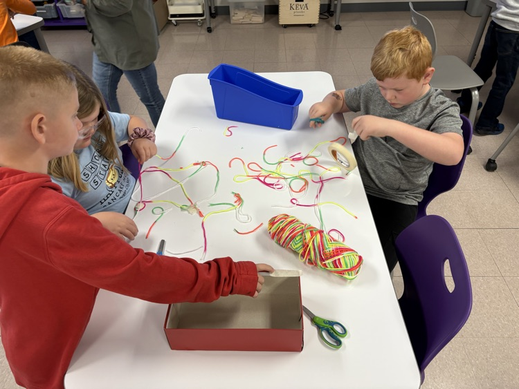 students building a spider web made of yarn