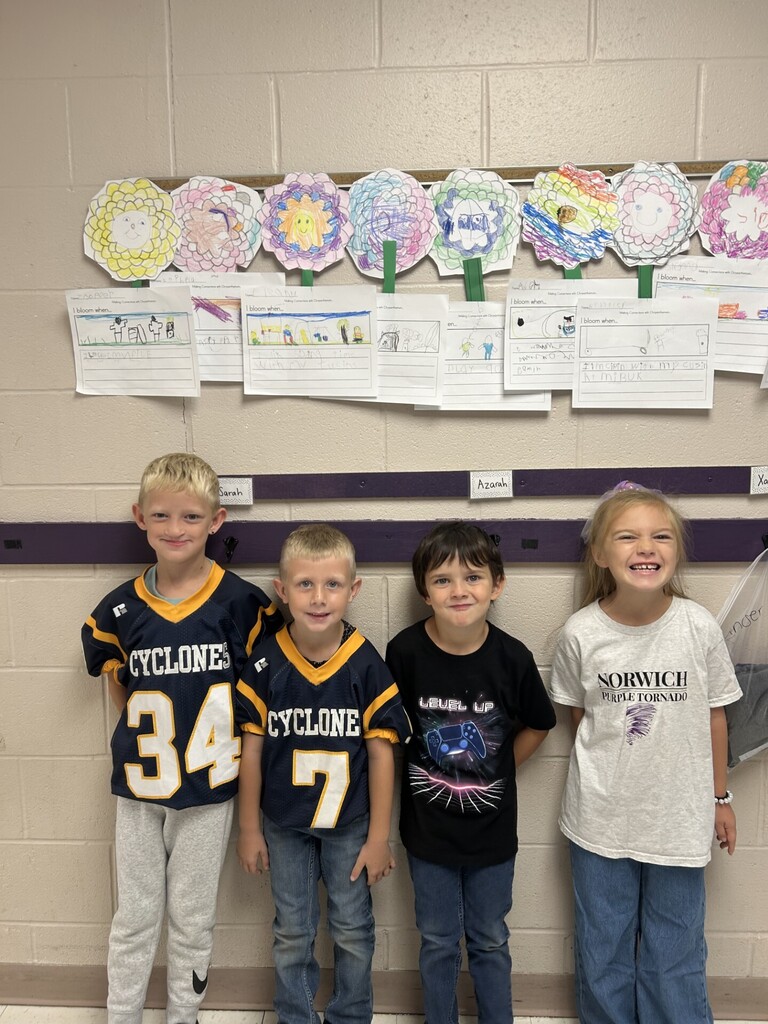 Photo of four students smiling in front of their Chrysanthemum crafts.