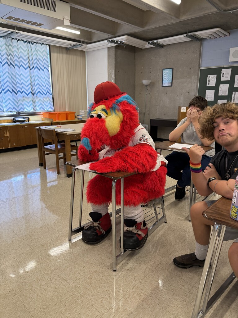 Gapper sitting in a student desk doing an assignment.