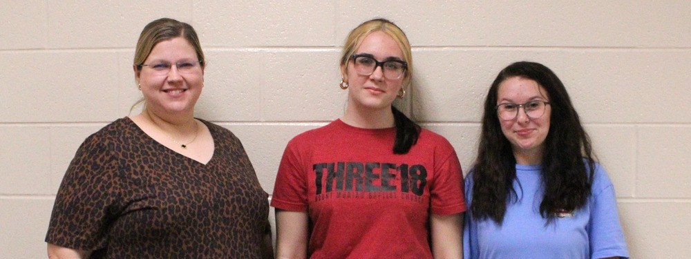 An SFHS teacher and two students smile in a group.
