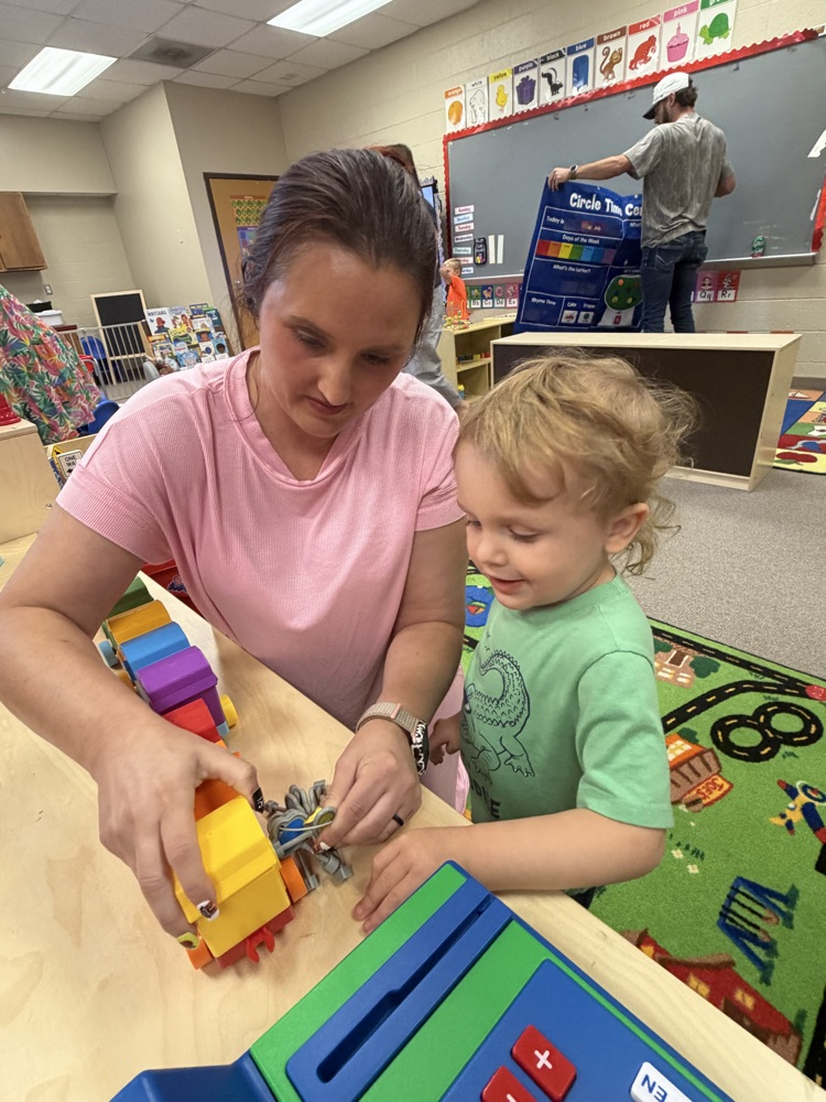 A staff member and a young child playing with a toy