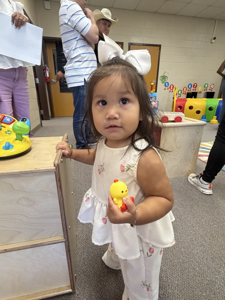 a young child holding a rubber duck looking at the camera.