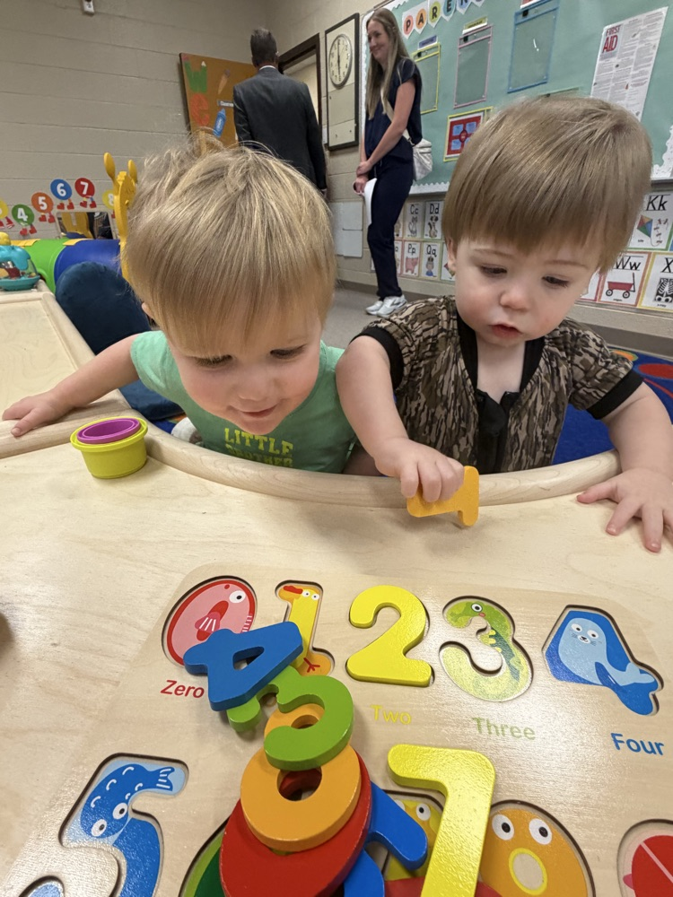 Two young children playing with a numbers puzzle