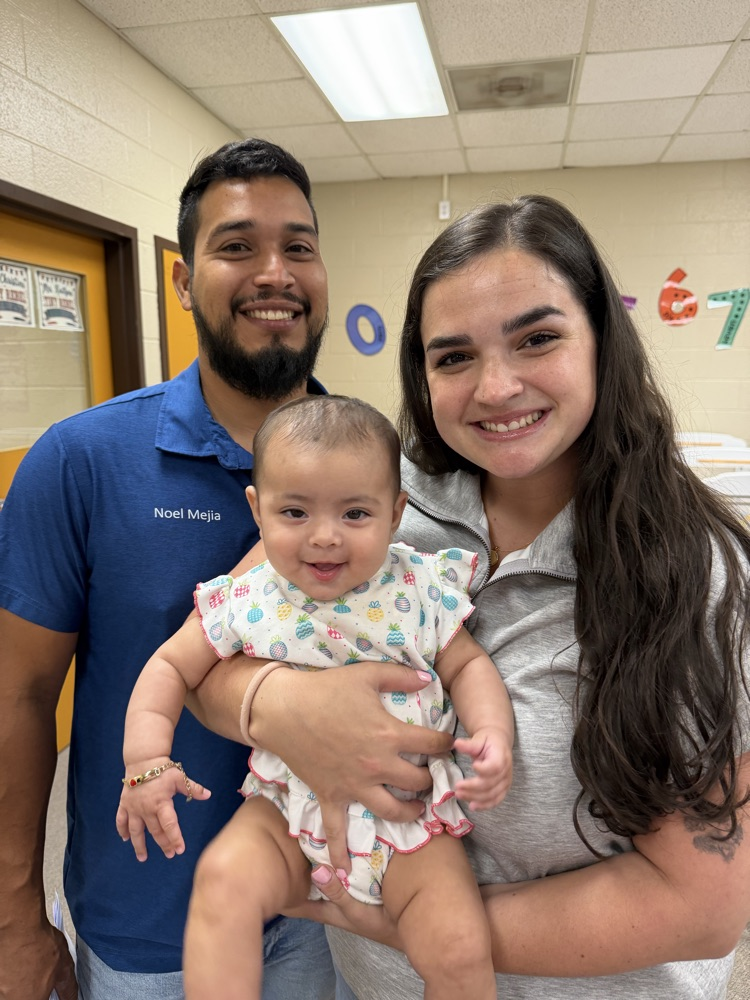 Parents holding their baby smiling at the camera.