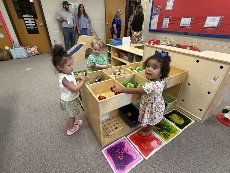 Three young children playing at a toy center