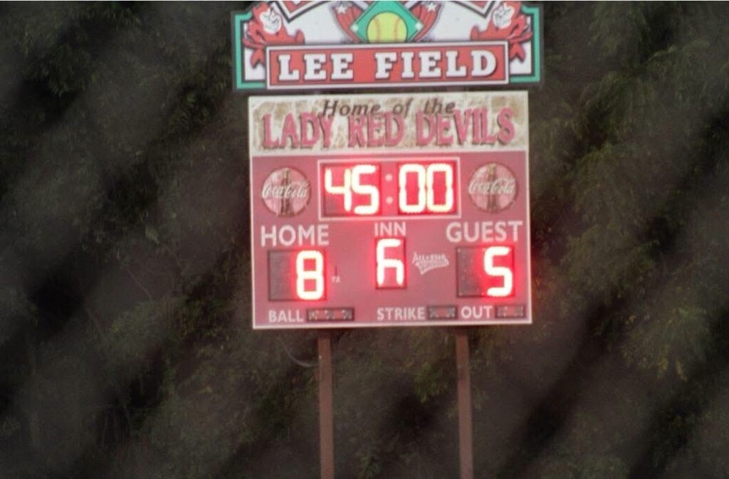 A scoreboard at Lee Field displays the Lady Red Devils’ score, with the home team leading 8–5.