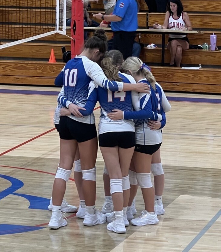 ChatGPT said: A group of young volleyball players huddling together on an indoor court.
