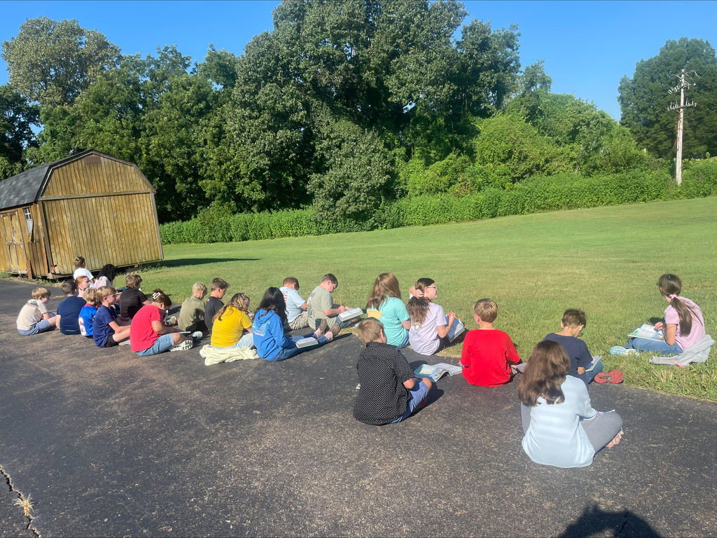 Students are outside on school grounds making observes of the living and nonliving organisms.