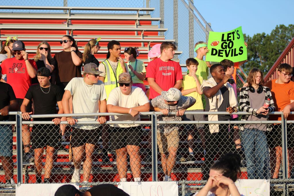 A group of students gather in the stands to watch a football game.