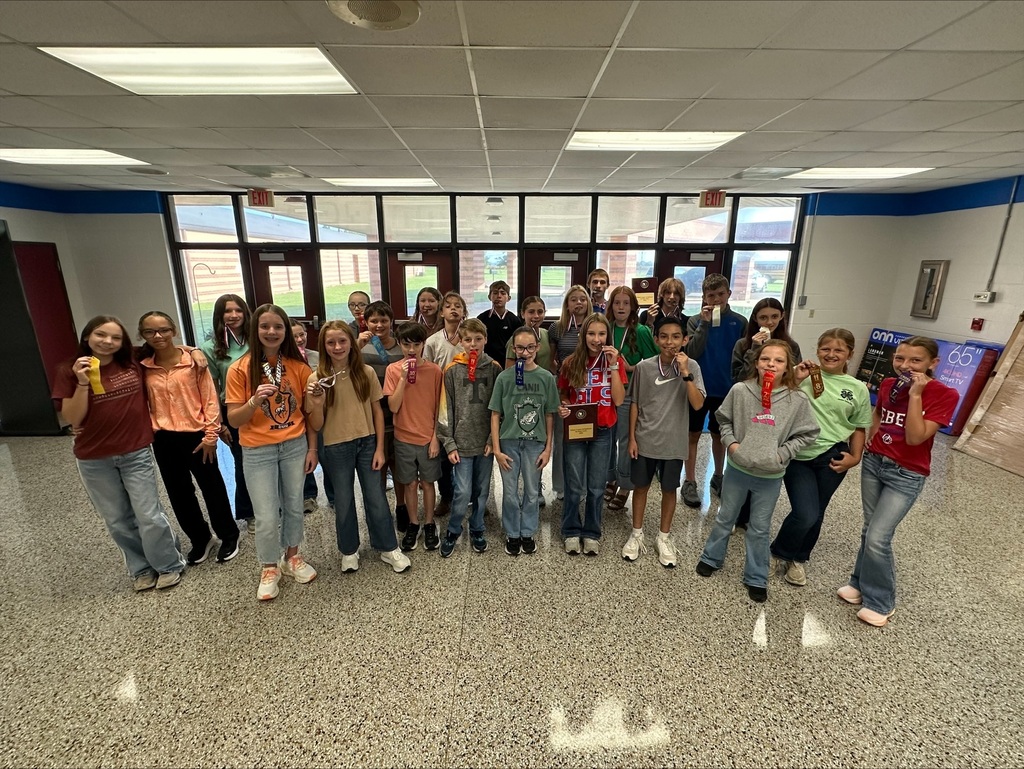 OCMS Cross Country Team gathered in school lobby to show their medals, plaques, and ribbons won at their most recent meet.