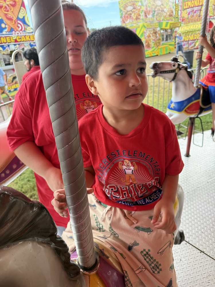 Students from Mrs. Alexis’s CDC class smiling while riding the carousel at the fair,