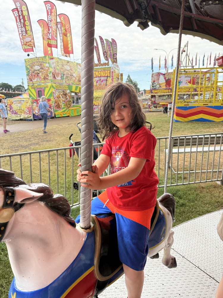 Students from Mrs. Alexis’s CDC class smiling while riding the carousel at the fair,